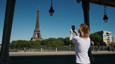 Kadın, Paris 'te gündüz vakti Eyfel Kulesi' nde akıllı telefon kullanarak selfie çekiyor. Yüksek kalite 4k görüntü