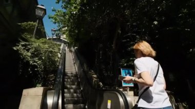 Genç turist kadın, metro istasyonunda ağır çekimde modern yürüyen merdivene binerken arkasına bakıyor. Yüksek kalite 4k görüntü