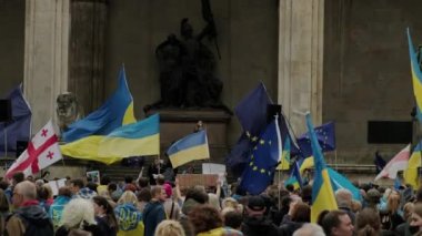 Ukrainian women and men protest on the streets of Munchen against the war and against the Russian leader Putin. people with placards, flags Europe, Deutschland Munchen, May 2022 .
