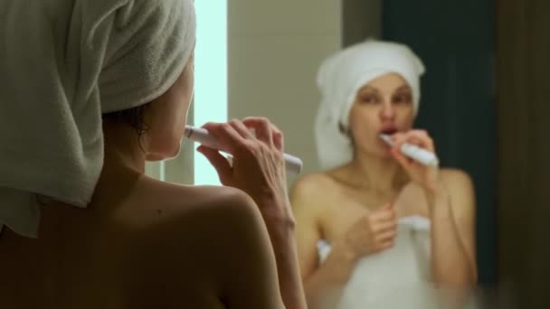 Mujer Con Toalla Baño Blanca Cabeza Cepillándose Los Dientes Mirando — Vídeo de stock