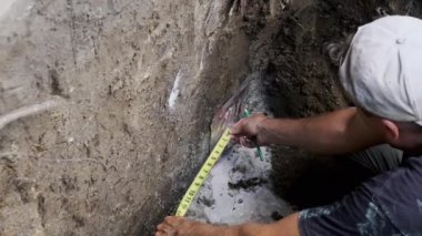 İnşaat işçisi duvarın uzunluğunu mezurayla ölçüyor. Yüksek kalite 4k görüntü