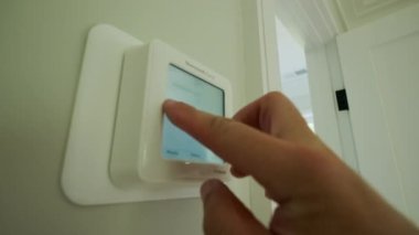 Man changing the temperature on a programmable hvac system on the house wall. High quality 4k footage