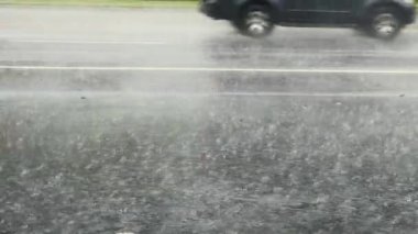 Slow Motion, heavy rain water drops falling into big puddle on asphalt, flooding the street. High quality 4k footage