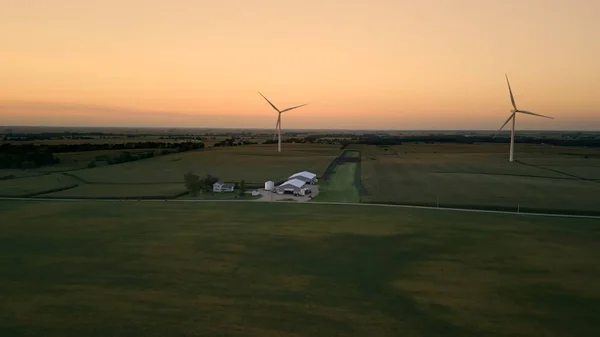 Aerial view of a wind park with wind turbines standing in a wheat field at sunset. . High quality 4k footage