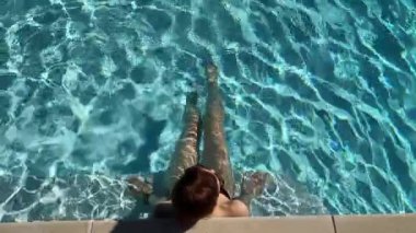 Sıcak bir yaz gününde, havuz kenarında mavi suda bir kadına karşı. Yüksek kalite 4k görüntü