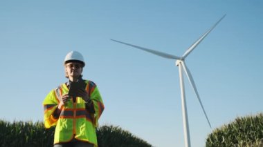 Rüzgâr tarlasında elinde tabletle bir mühendis rüzgar türbinini ayarlıyor. Yüksek kalite 4k görüntü
