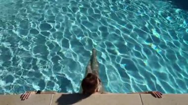 Sıcak bir yaz gününde, havuz kenarında mavi suda bir kadına karşı. Yüksek kalite 4k görüntü