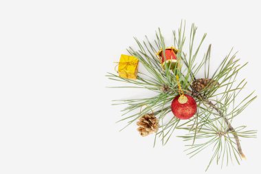 Düz bir Noel manzarası vardı. Ağaç dalları ve noel süslemeleri ile üst manzara çerçevesi. Beyaz arka planda bir köknar dalı, kırmızı oyuncaklar ve konilerin Noel kompozisyonu. İzole edilmiş