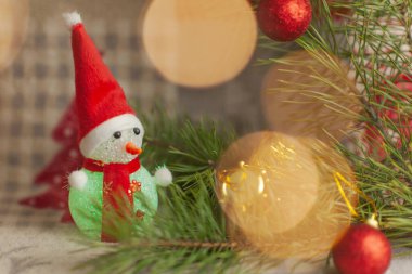 Noel ağacı ışıklarının önünde odağını kaybetmiş ahşap kayaklı kardan adam bebeği. Yılbaşı kardan adamı Noel ağacının yanında.