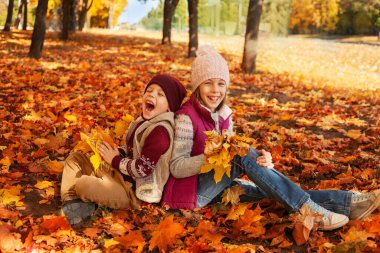 happy boy and girl laughing on the background of autumn leaves in the park. Family Having Fun Outdoors. Yellow Trees and Leaves. Freedom Concept.