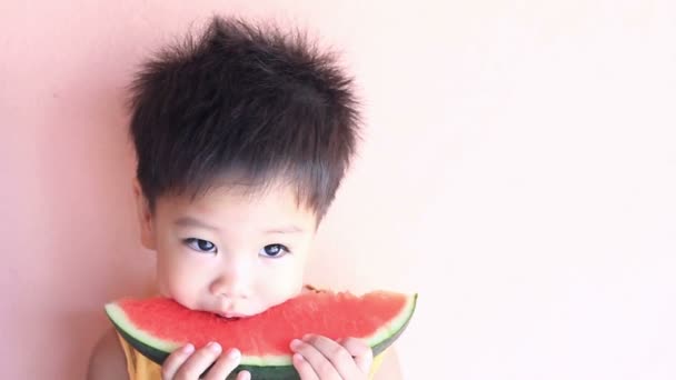 Маленький азиатский мальчик ест арбуз — стоковое видео