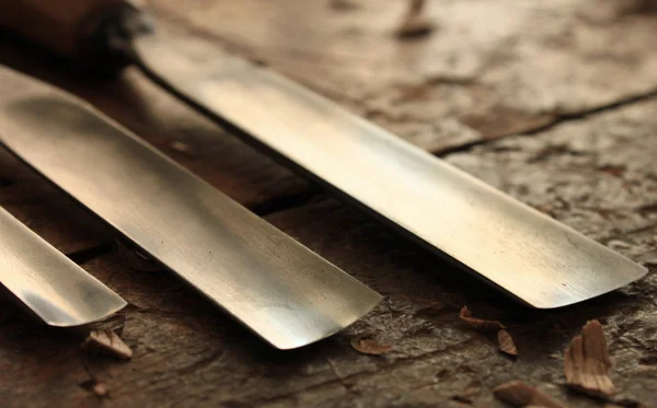 Carpenter wood chisel tool with loose shavings on old weathered wooden workbench — Stock Photo, Image