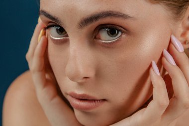 Genç bir kız, kusursuz ciltli bir kadın. Stüdyoda izole edilmiş bir kız. Moda, doğal çıplak makyajlı ve uzun kirpikli güzellik mankeni portresi. Mavi, sağlam bir arka plan. Portreyi kapat