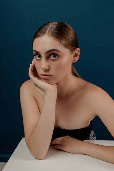 Молодая девушка с чистой идеальной кожей. Изолированная девушка в студии. Мода на голову. Портрет модели красоты с натуральным обнаженным макияжем и длинными ресницами. Синий твердый фон.