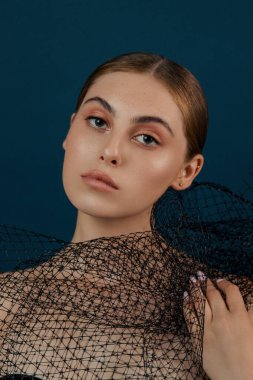 Temiz ciltli bir kadın. Stüdyoda izole edilmiş bir kız. Moda, doğal çıplak makyajlı ve uzun kirpikli güzellik mankeni portresi. Mavi, sağlam bir arka plan. Göz kamaştırıcı bir kadın. El pozları