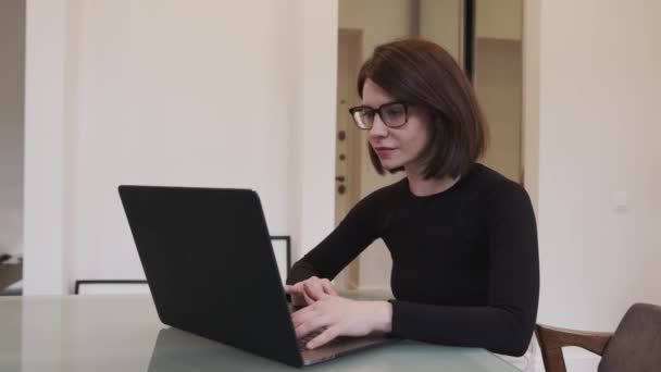 Femme d'affaires dans les lunettes avec ordinateur portable sur la table de travail dans le bureau à domicile — Video