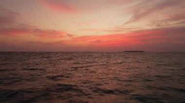 Dalgalı okyanus ve panoramik pembe gökyüzü üzerinden Maldivler 'in insansız hava aracı görüntüsü