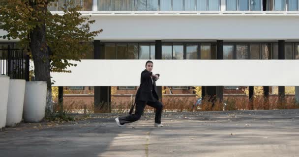 Attractive businesswoman in formal black suit is dancing outside the office, financial district, modern constructivist building on background. The concept of urban city scene. — Stockvideo
