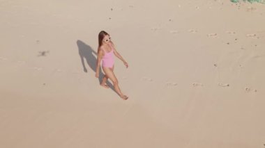 Yüzmeye, okyanusa ve sahile giden mayo giymiş bir kadının robot resmi.