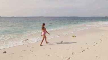 Mayolu bir kadın Maldivler adasındaki sahil şeridinde yürüyor.