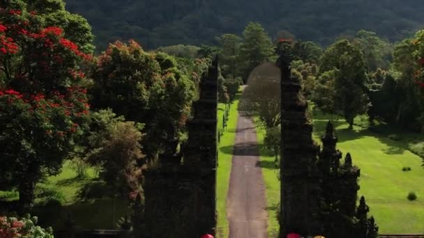 Воздушный кадр индуистского входа, беспилотник летит к холмам. Бали, Индонезия. Вид на живописный ландшафт и дорогу. — стоковое видео