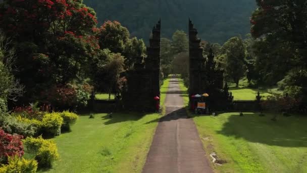 Воздушный кадр индуистского входа, беспилотник летит к холмам. Бали, Индонезия. Вид на живописный ландшафт и дорогу. — стоковое видео