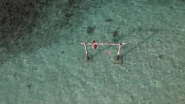 Drone volar sobre columpio en el océano con una mujer, olas y la isla tropical — Vídeos de Stock