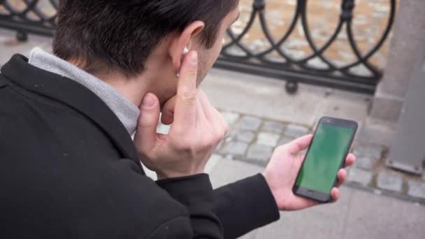 Biznesmen Korzystający Smartfona Zielonym Ekranem Kluczem Chromowym Bezprzewodowymi Słuchawkami Siedzi — Wideo stockowe