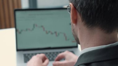 Omzunda cihazla iş adamı ekrana doğru kayıyor. Borsa şamdanları, dinamikleri, finansal analizleri. Çevrimiçi ticaret kavramı