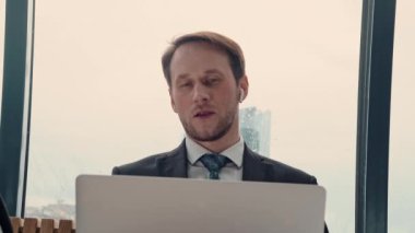 İş adamı bir video konferansında konuşuyor, çevrimiçi iletişim, çalışma süreci, dışarıda yağmurlu ve bulutlu.
