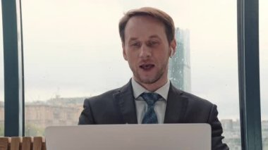 İş adamı bir video konferansında konuşuyor, çevrimiçi iletişim, çalışma süreci, dışarıda yağmurlu ve bulutlu.