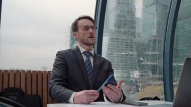 İş adamı bir video konferansında konuşuyor, çevrimiçi iletişim, çalışma süreci, dışarıda yağmurlu ve bulutlu.