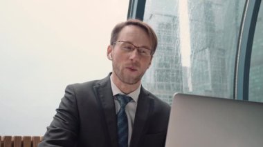 İş adamı bir video konferansında konuşuyor, çevrimiçi iletişim, çalışma süreci, dışarıda yağmurlu ve bulutlu.