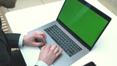 Dizüstü bilgisayarda yazan ve yeşil ekrana bakan bir iş adamının omzunun üstünden. Ofisteki kişi bilgisayar, kromo anahtar ekranı kullanıyor