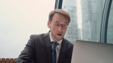 İş adamı bir video konferansında konuşuyor, çevrimiçi iletişim, çalışma süreci, dışarıda yağmurlu ve bulutlu.