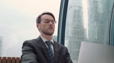 İş adamı bir video konferansında konuşuyor, çevrimiçi iletişim, çalışma süreci, dışarıda yağmurlu ve bulutlu.