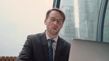İş adamı bir video konferansında konuşuyor, çevrimiçi iletişim, çalışma süreci, dışarıda yağmurlu ve bulutlu.