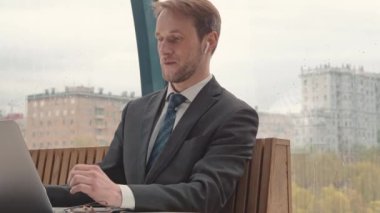İşadamı dizüstü bilgisayar, sindirme alanı, arka planda şehir, yağmurlu sonbahar havası kullanıyor..