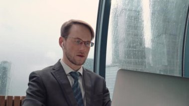 İş adamı bir video konferansında konuşuyor, çevrimiçi iletişim, çalışma süreci, dışarıda yağmurlu ve bulutlu.