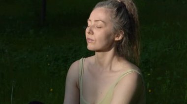Genç ve formda bir kadın sabah vakti parkta yoga yapıyor. Güzel kız dışarıda yoga egzersizi yapıyor. Gerçek zamanlı.