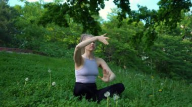 Genç ve formda bir kadın sabah vakti parkta yoga yapıyor. Güzel kız dışarıda yoga egzersizi yapıyor. Gerçek zamanlı.