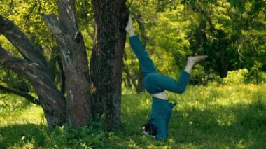 Genç ve formda bir kadın sabah vakti parkta yoga yapıyor. Güzel kız dışarıda yoga egzersizi yapıyor. Gerçek zamanlı.