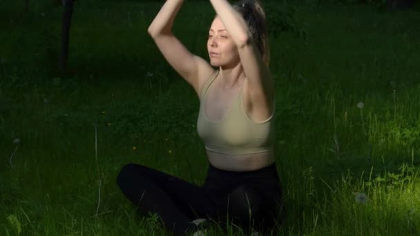 朝の公園でヨガを練習する若いフィットの女性 屋外でヨガの練習をするかなりの女の子 リアルタイム — ストック動画