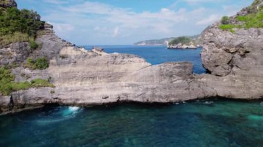Kayalık uçurumun havadan görüntüsü. Hint Okyanusu kıyısında. Güzel doğa ve yaz tatili konsepti. İnsansız hava aracı soldan sağa uçuyor. Bali 'deki Nusa Penida Adası