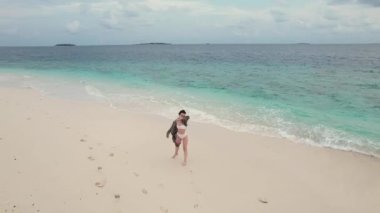 Sahilde dans eden enerjik bir kadının havadan çekimi, Maldivler 'deki Hint okyanusunun silueti ve turkuaz dalgaları. Üst düzey seyahat hedefi kavramı