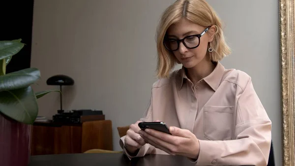 Voksen Kvinne Briller Rosa Skjorte Som Holder Smarttelefon Hendene Skriver – stockfoto