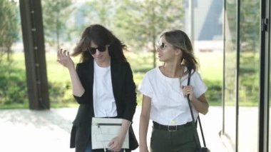 İki çekici genç kadın güneş gözlüğü takıyor blogcular moda ve rahat kıyafetler birlikte sokak moda trendleri yaz Park tartışırken yürüyor. Yavaş hareket orta atış izleme