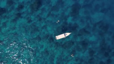 Sürat teknesi ve yüzen turistlerle turkuaz mavi su denizi, havadan insansız hava aracı görüntüsü. Doğada bir gemi okyanus manzarası. Yaz tatili seyahati, tatil beldesi, turizm.