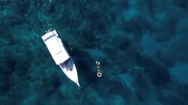 Sürat teknesi ve yüzen turistlerle turkuaz mavi su denizi, havadan insansız hava aracı görüntüsü. Doğada bir gemi okyanus manzarası. Yaz tatili seyahati, tatil beldesi, turizm.