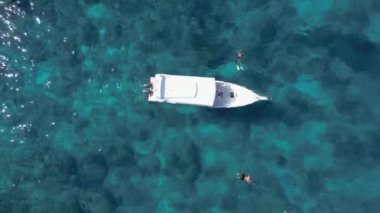 Sürat teknesi ve yüzen turistlerle turkuaz mavi su denizi, havadan insansız hava aracı görüntüsü. Doğada bir gemi okyanus manzarası. Yaz tatili seyahati, tatil beldesi, turizm.